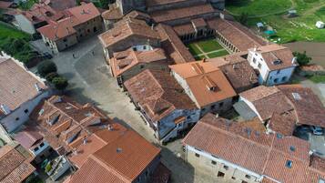 Vista aérea de un pueblo histórico con edificios muy juntos y techos de tejas rojas, y una plaza central.