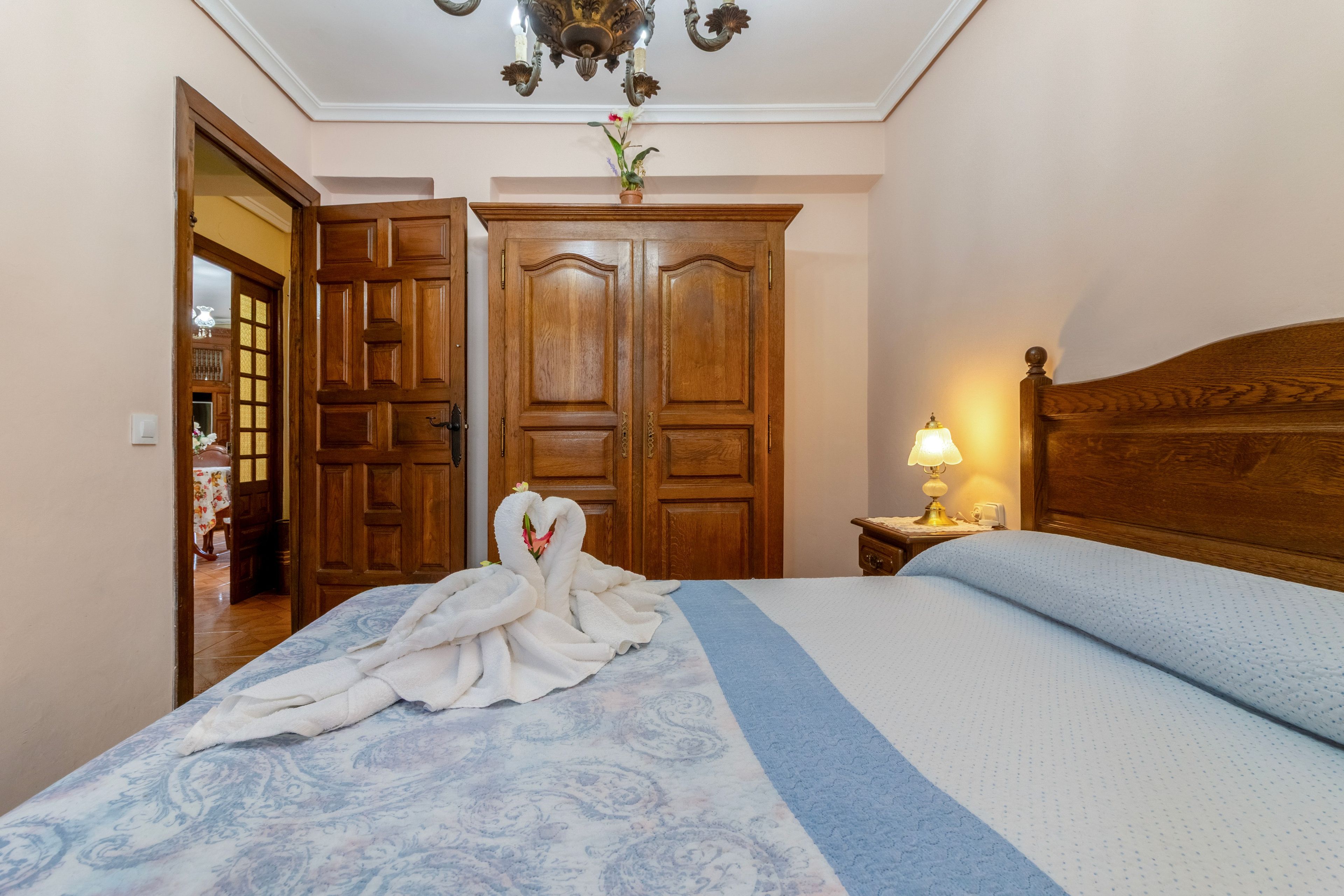 Een hotelkamer met een groot bed, een houten garderobe en een kroonluchter.