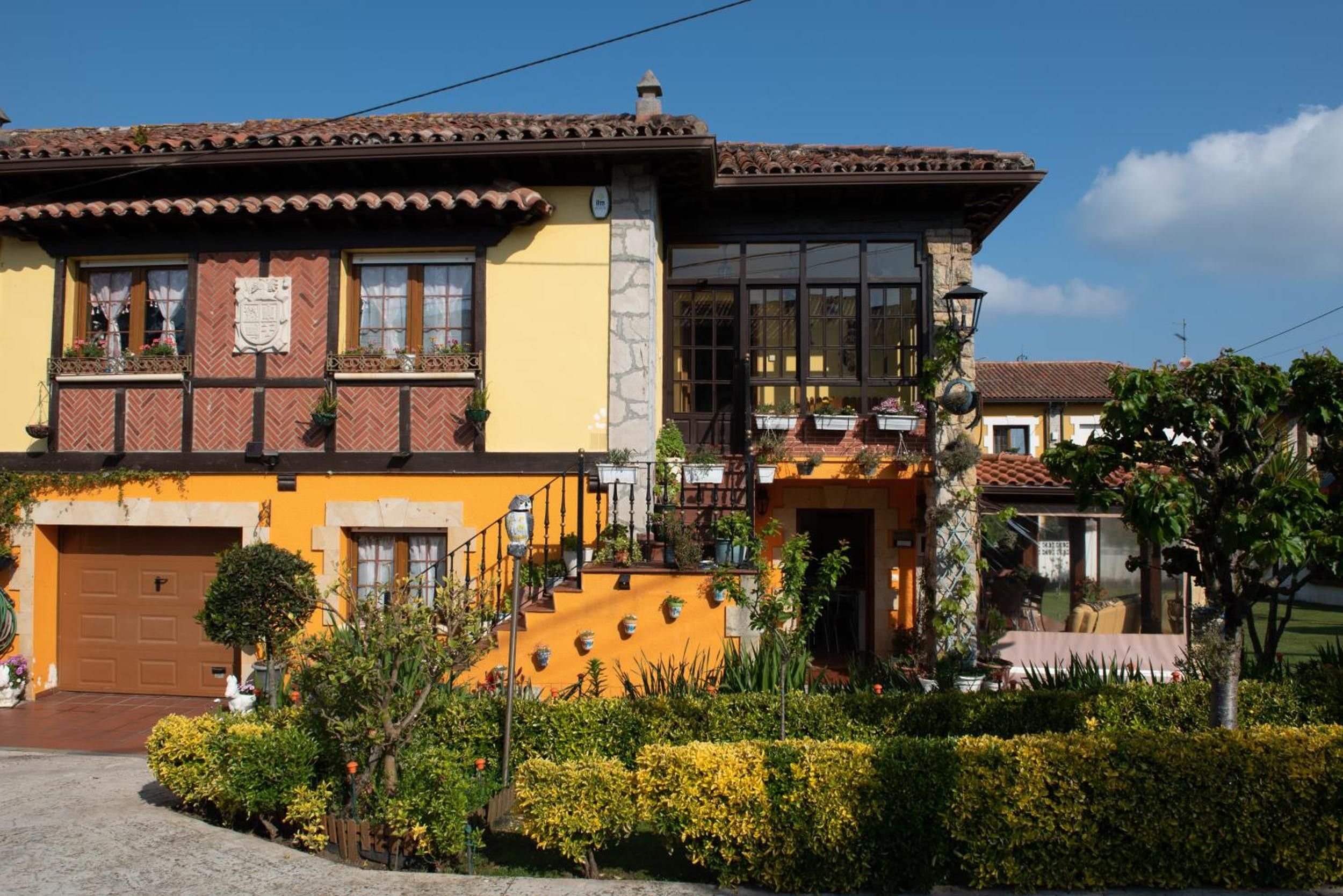 Un edificio de dos pisos con fachada amarilla, una puerta marrón y una escalera que lleva al piso superior.
