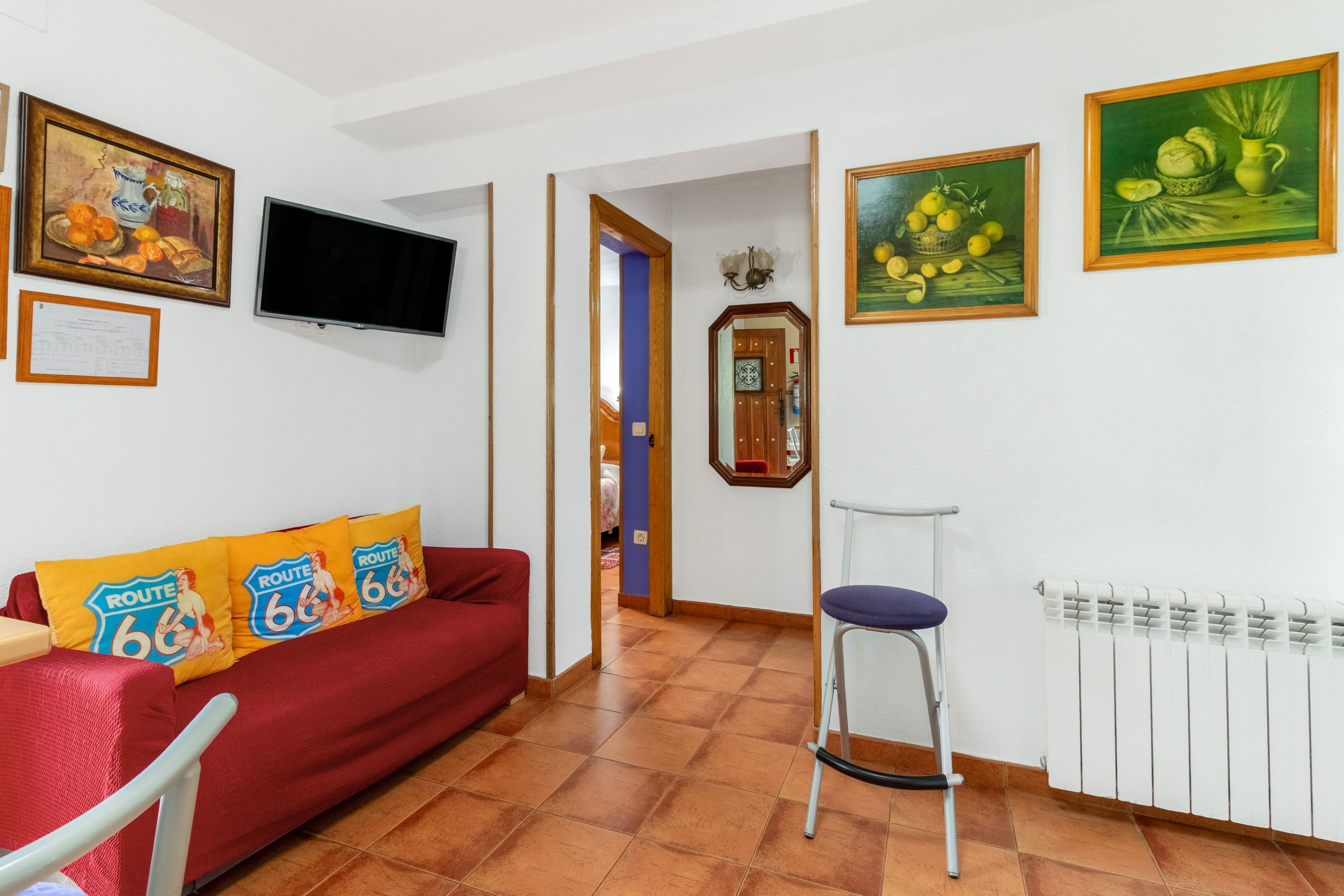 Een woonkamer met een rode bank, een televisie en kunstwerken aan de wanden.