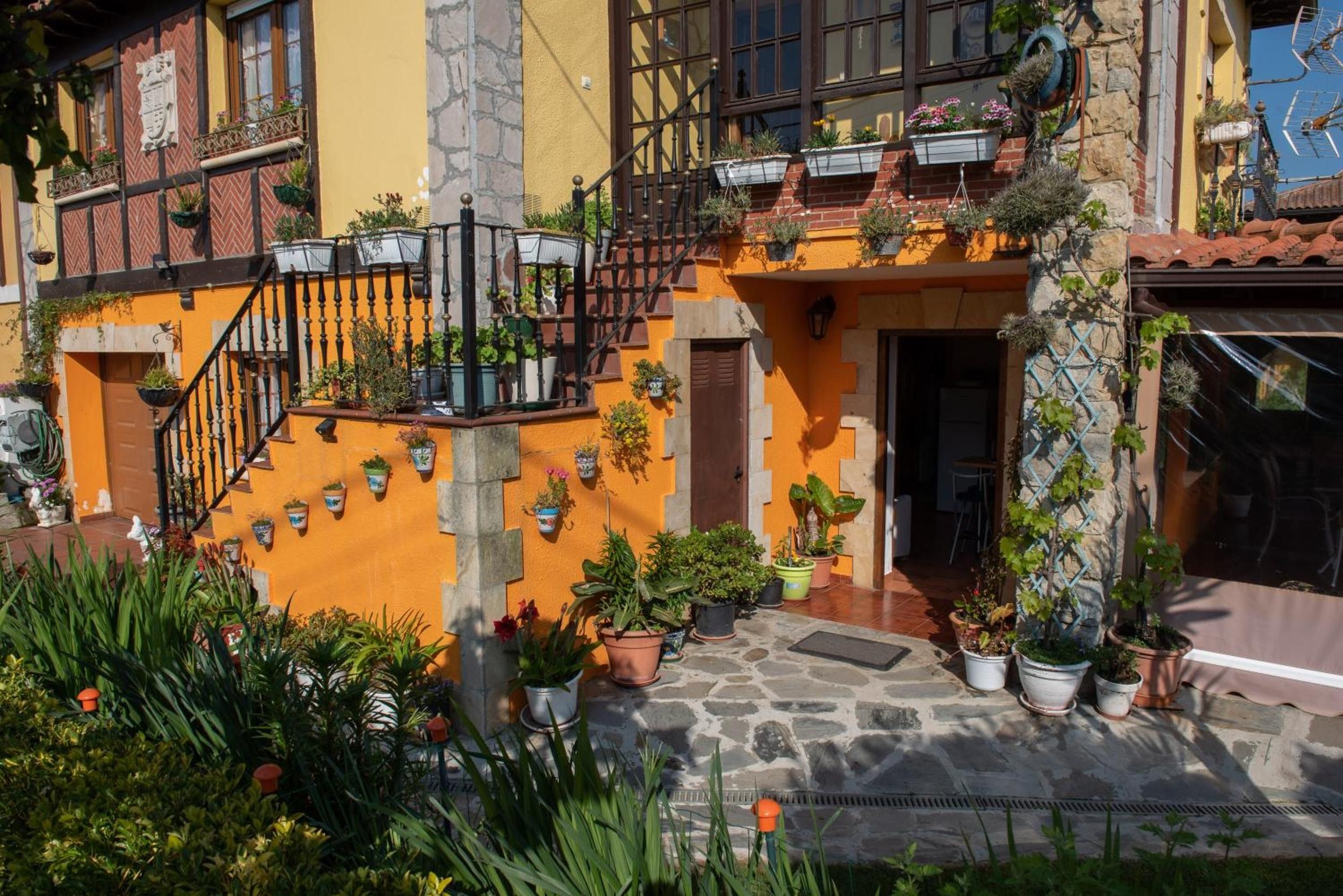 A multi-story building with balconies, potted plants, and a stone staircase.