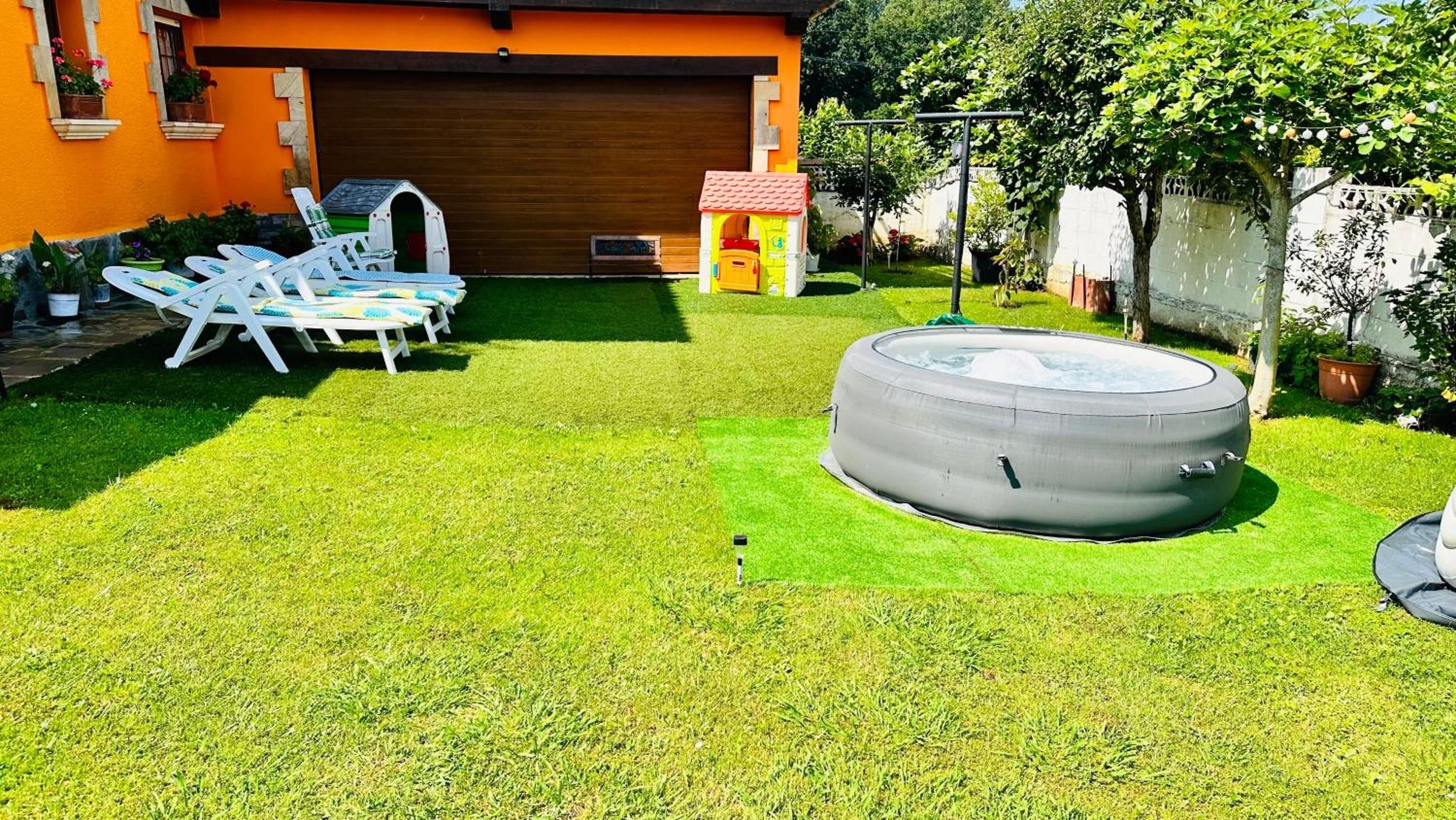 A backyard with a hot tub, lawn chairs, and a small playhouse.
