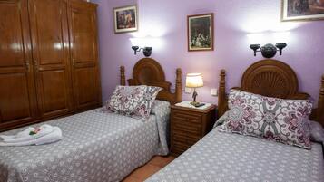 Un dormitorio con dos camas, cabeceros de madera, un armario y lámparas de pared.