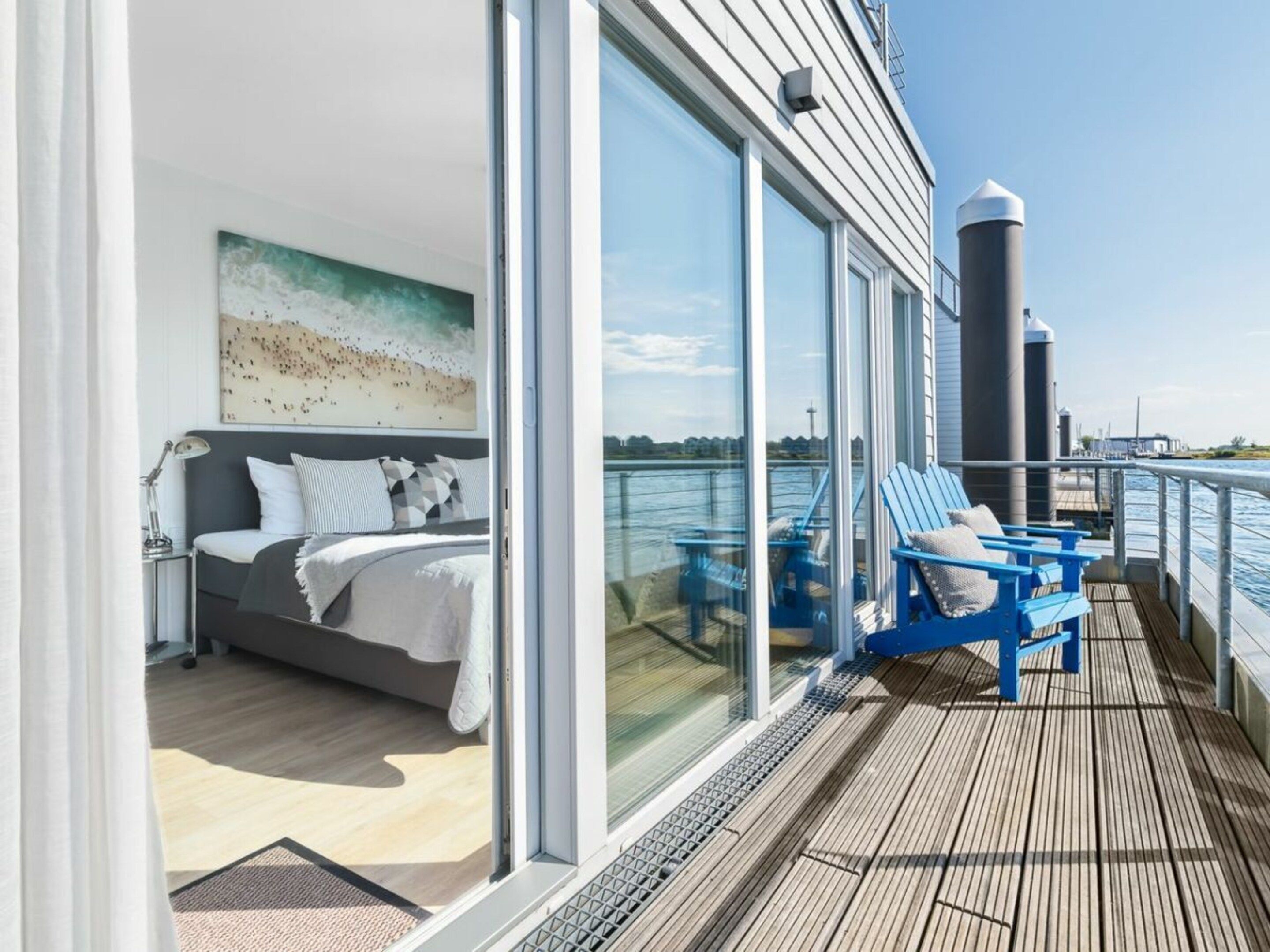 A bedroom with a bed, a nightstand, and a window overlooking a body of water.