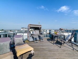 Eine Terrasse mit Sitzgelegenheiten, einem Tisch und Blick auf das Wasser.
