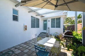 Eine Terrasse mit Tisch, Stühlen und einem Grill.