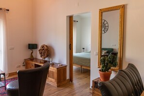 A room with a bed, a desk with a lamp, a chair, a mirror, and a potted plant. - Farm Lodges Olive, Casa Alfarrobeira, Moncarapacho Countryside (moncarapacho)