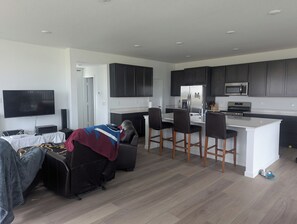 Et moderne køkken med mørke skabe, en hvid bordplade og en indbygget mikroovn.