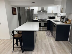 A modern kitchen with a central island, stainless steel appliances, and a microwave. - Aura Basement Unit 2 / Self-Check-In, Wi-Fi, and 1 Free Parking Space / Niagara Falls, ON (Niagara Falls)