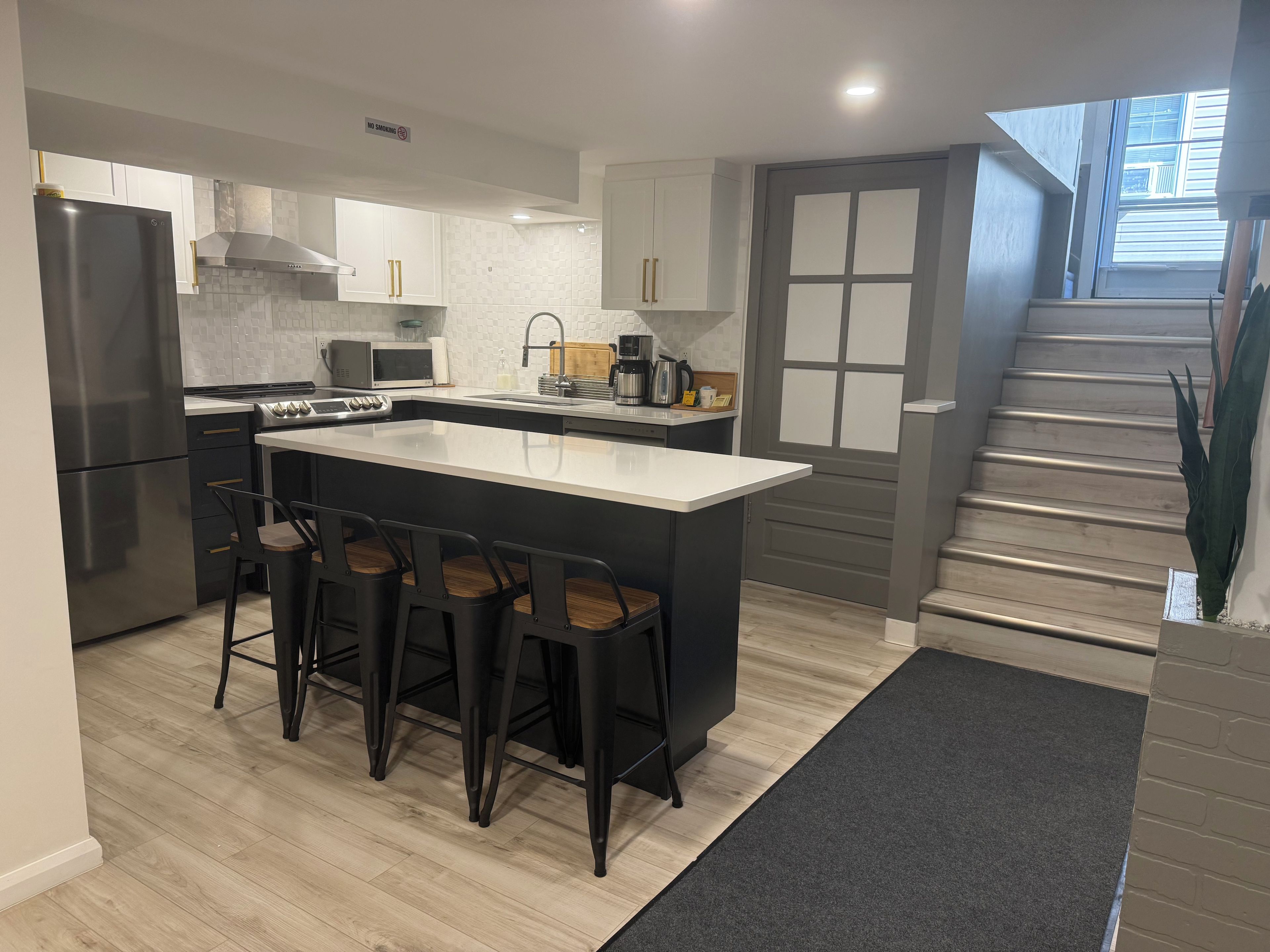 A modern kitchen with a central island, bar stools, a microwave, and a stove.