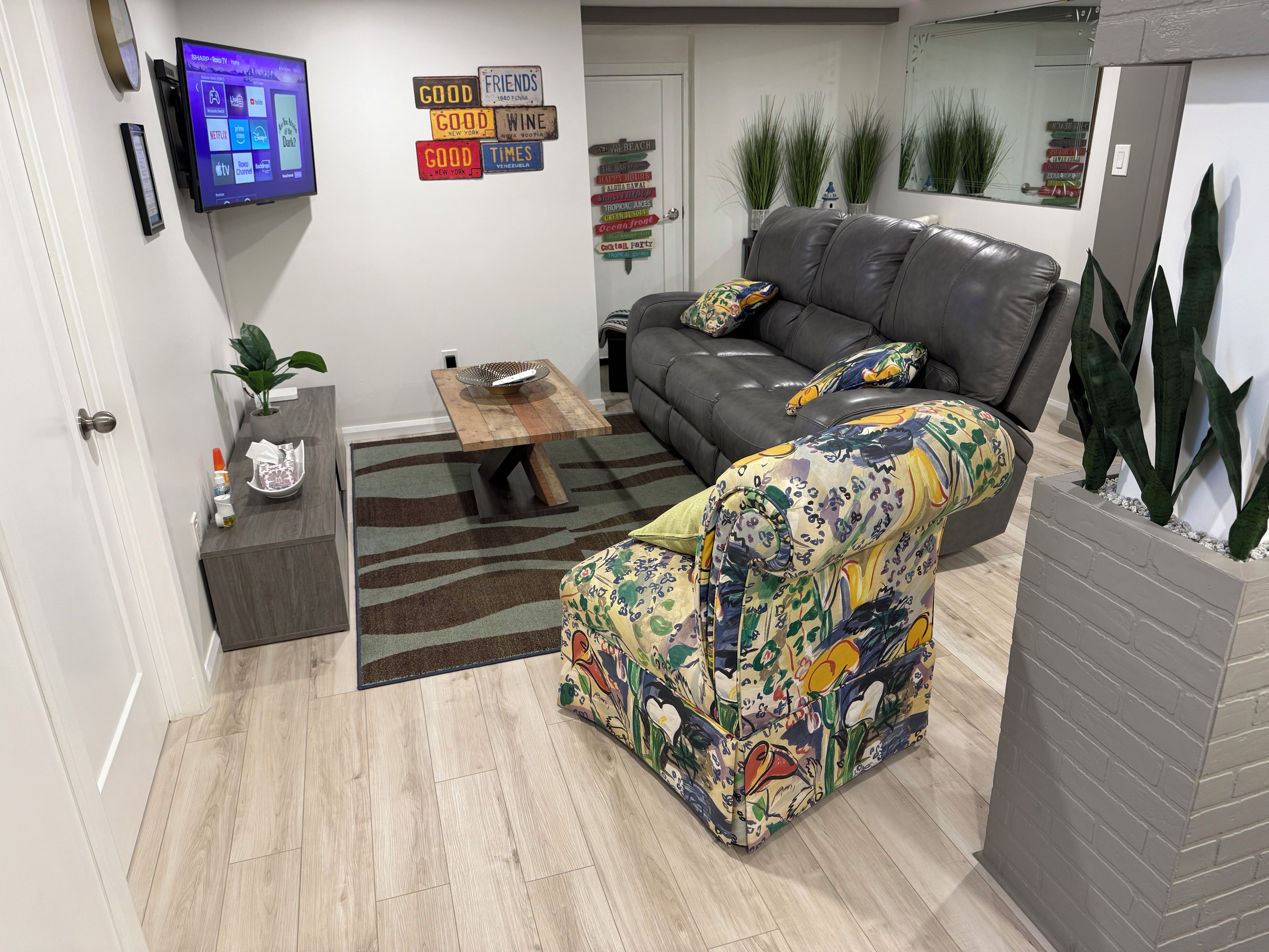 Ein Wohnzimmer mit Sofa, Couchtisch, Flachbildfernseher und einer Wand mit dekorativen Schildern.