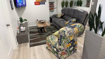 Ein Wohnzimmer mit Sofa, Couchtisch, Flachbildfernseher und einer Wand mit dekorativen Schildern.