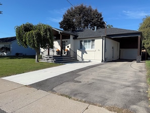 Une maison d’habitation avec un porche à l’avant, un garage et une allée.