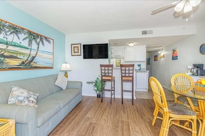 A compact living space with a sofa, dining table, chairs, a small kitchen, and a ceiling fan. - Ocean Views & Resort-Style Relaxation at Meridian Plaza 507 (Myrtle Beach)