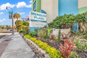 A sign for Meridian Plaza with a welcoming message, surrounded by a landscaped garden with various plants. - Ocean Views & Coastal Comfort at Meridian Plaza 508 (Myrtle Beach)