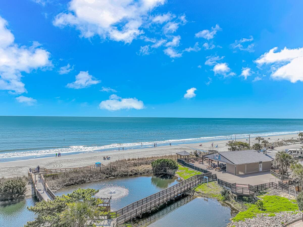 A coastal area with a beach, a small dock, and a building with a flat roof.