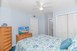 Ein Schlafzimmer mit einem Bett, einem Schminktisch, einem Fernseher, einem Deckenventilator und einem Kleiderschrank.