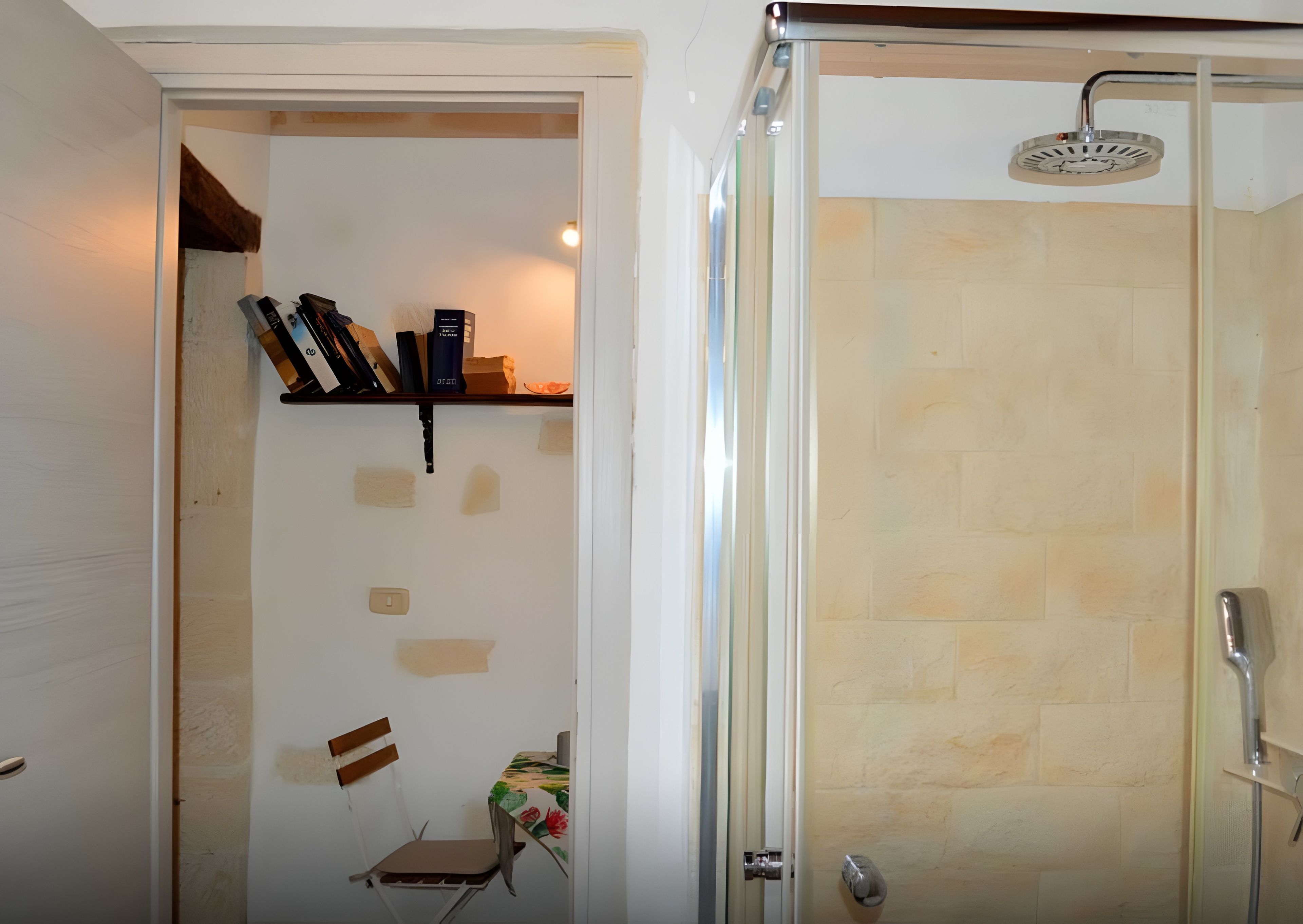 Une salle de bain avec une douche, une chaise et une étagère contenant des livres et une boîte.