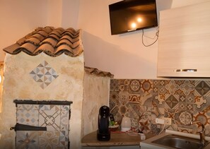Eine Küche mit gefliestem Fliesenspiegel, einer Kaffeemaschine, einem an der Wand befestigten Fernseher und einem modernen Schrank.
