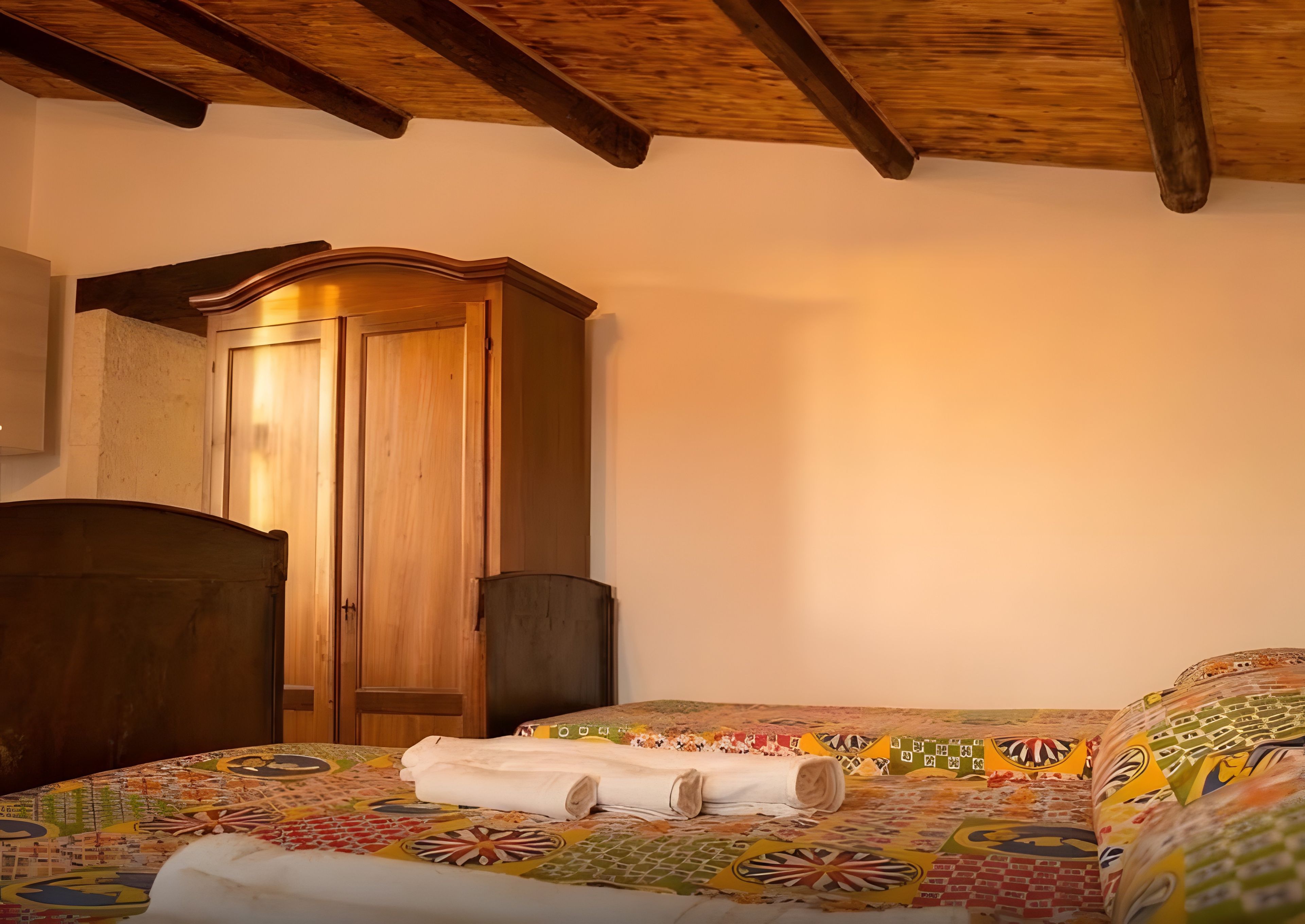 Una stanza con un'armadiatura in legno, un letto con copriletto colorato e un soffitto in legno.