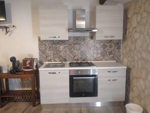 Cuina compacta amb fogó a gas, forn i un rebedor de rajola.