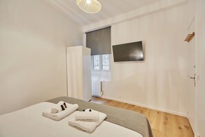 Ein Schlafzimmer mit einem Bett, einem an der Wand montierten Fernseher und einem Fenster mit Blick.
