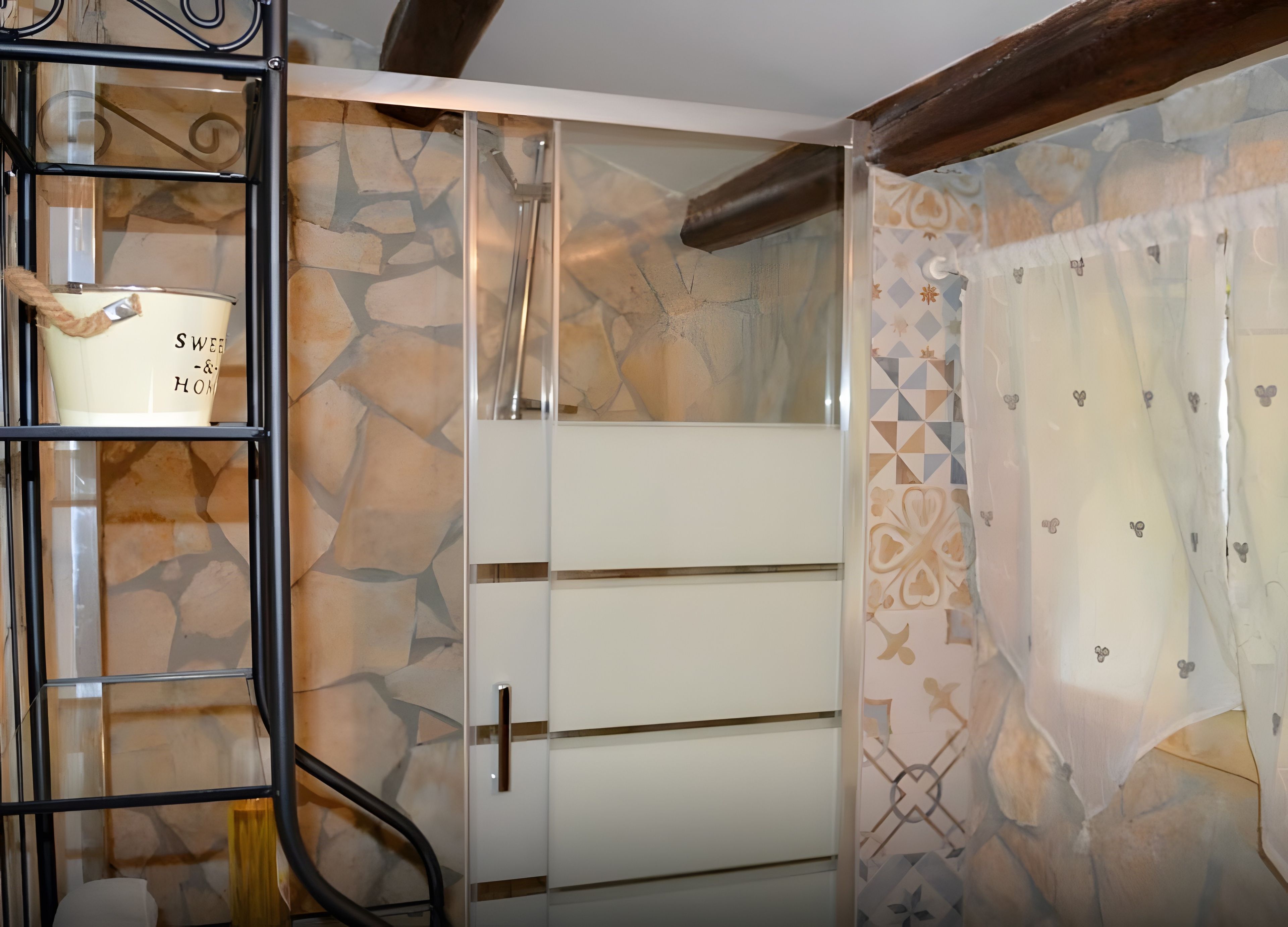 Une pièce avec un mur dont le motif rappelle la pierre, un meuble blanc doté d’une poignée et un rideau à motifs.
