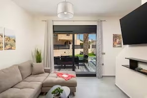 Ett modernt vardagsrum med en soffa, ett soffbord och en tv som är monterad på väggen.
