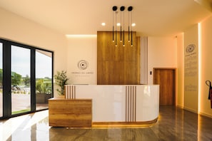Un mostrador de recepción con un panel de madera de fondo, un logotipo y una pared con texto.
