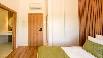 Un dormitorio con una puerta de madera, una cama con ropa de cama verde y un armario blanco.