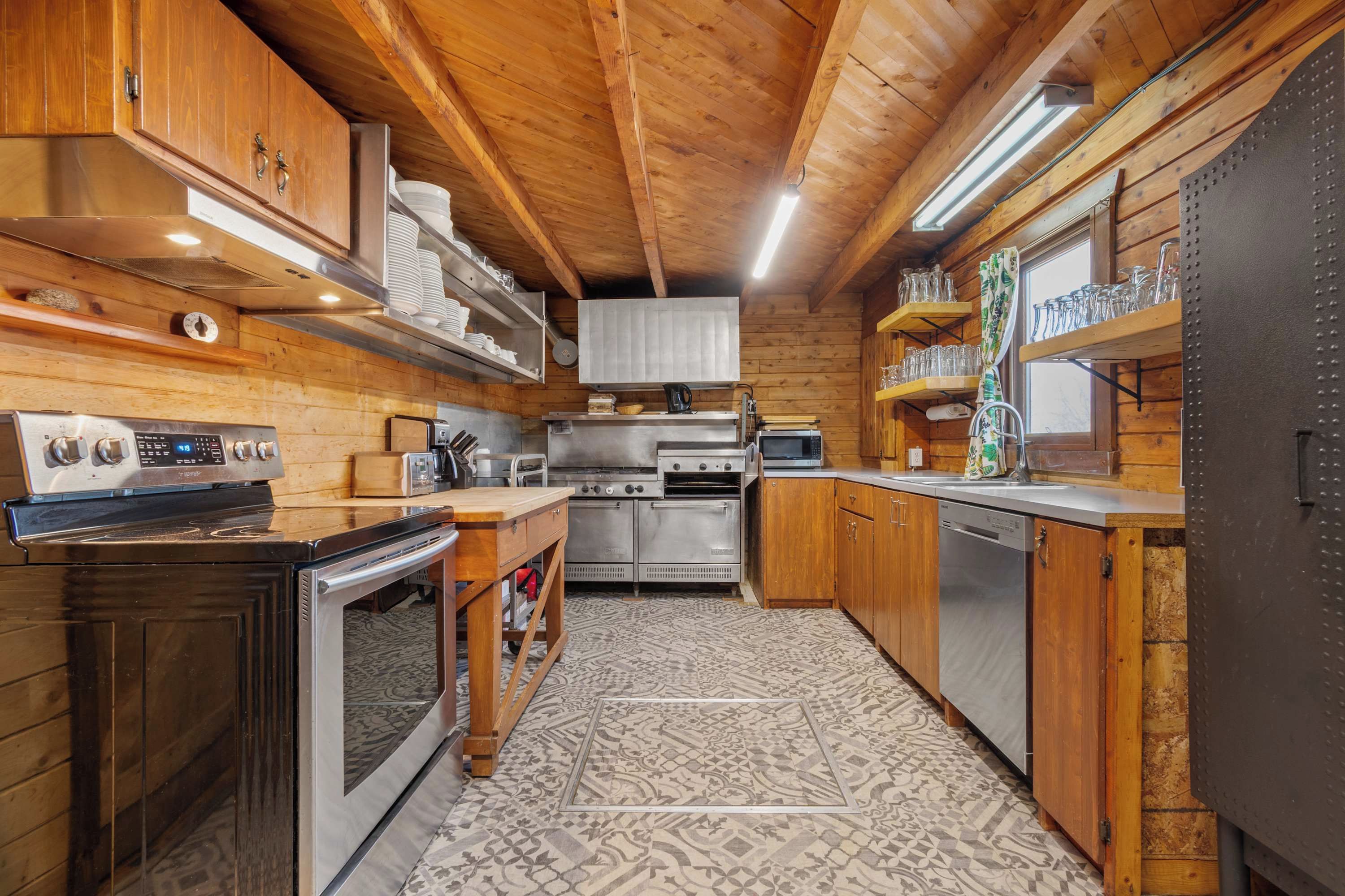 Una cocina compacta con gabinetes de madera, electrodomésticos de acero inoxidable y piso estampado.