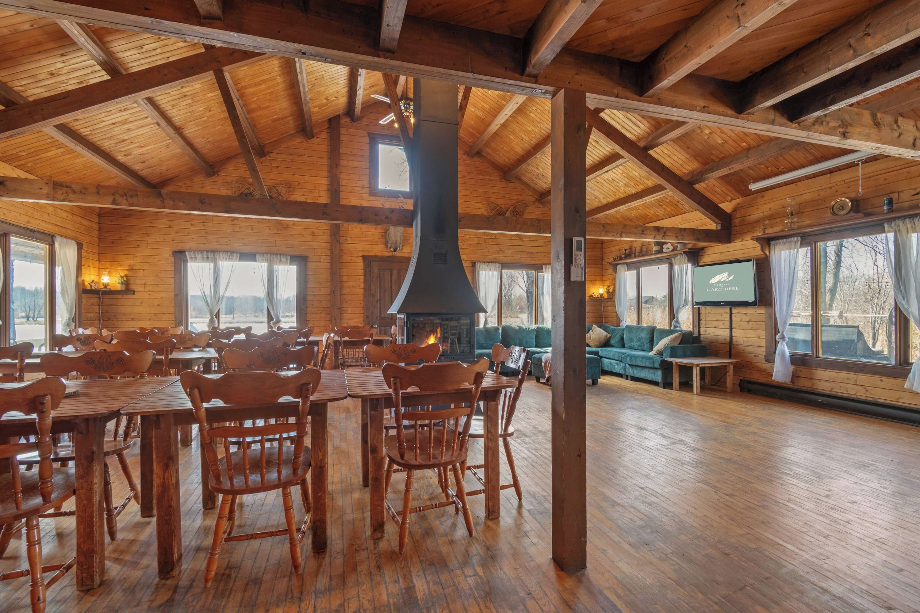 Ein großzügiger Holzraum mit hoher Decke, Kamin und Fernseher.