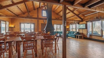 Ein großzügiger Holzraum mit hoher Decke, Kamin und Fernseher.