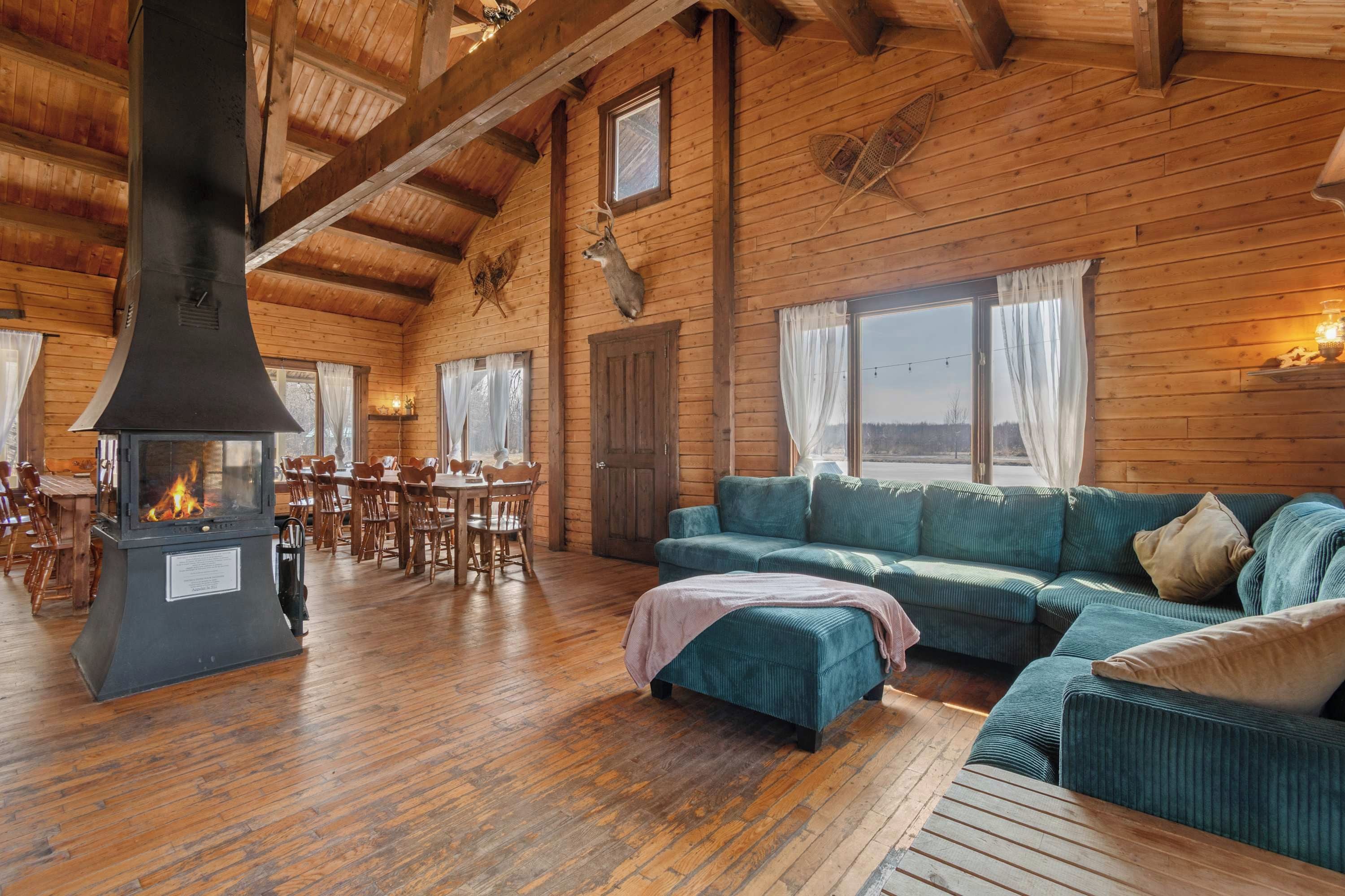 Ein rustikales Blockhaus-Interieur mit großem Kamin, Holzwänden, einem Essbereich und einer gemütlichen Sitzecke.