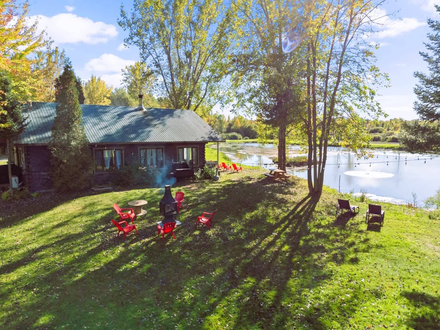 A lakeside cabin with outdoor seating and a view of the water.