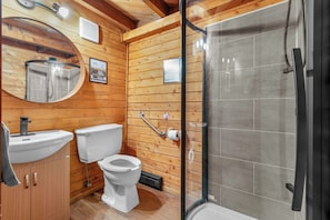 Un intérieur en bois comprenant des toilettes, un lavabo et un espace douche.