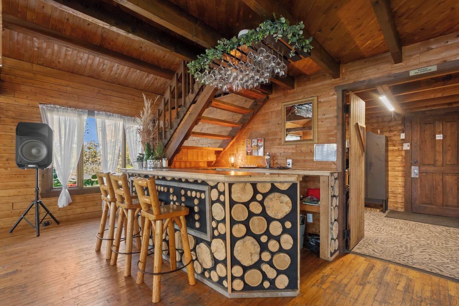 Ein Holzinnenraum mit Barbereich, Holzstühlen, einer Treppe und einem Lautsprecher.