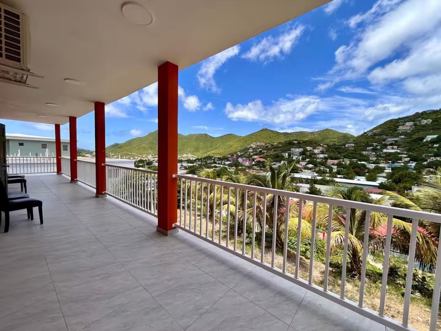 A covered balcony with a view of a hillside town.