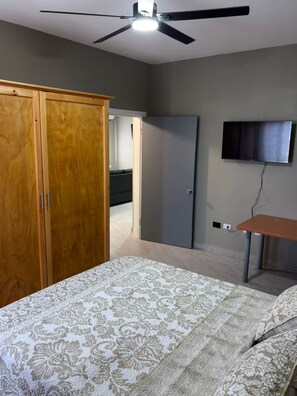 Ein Schlafzimmer mit Bett, Kleiderschrank, Fernseher und Schreibtisch.