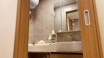 A modern bathroom with a large mirror, a white sink, and a towel rack.