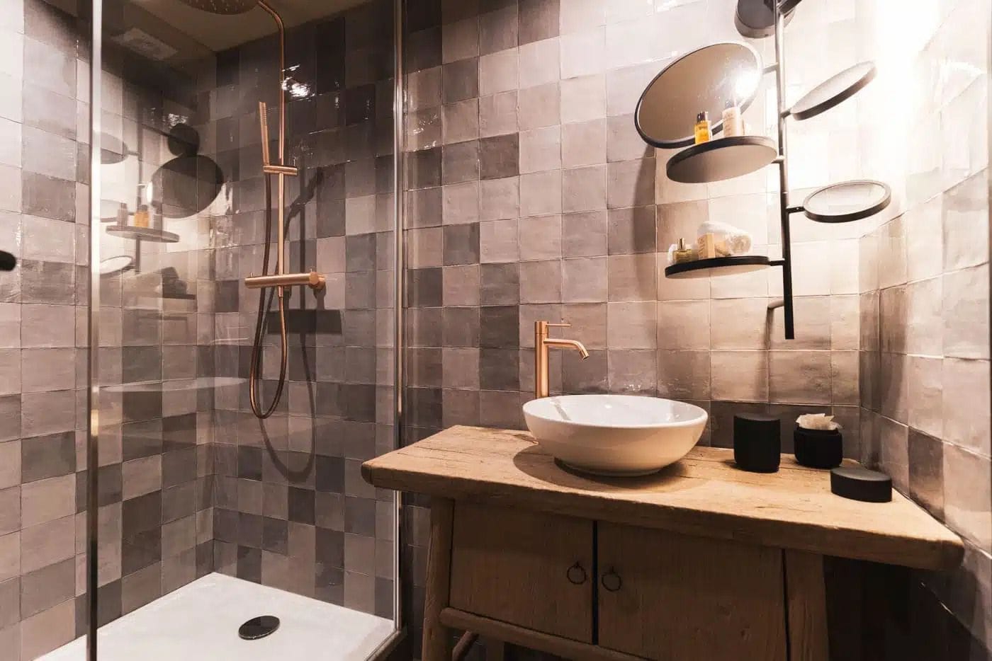 Une salle de bain moderne dotée d’une douche à parois de verre, d’un meuble-lavabo en bois avec un vasque et d’un miroir fixé au mur.