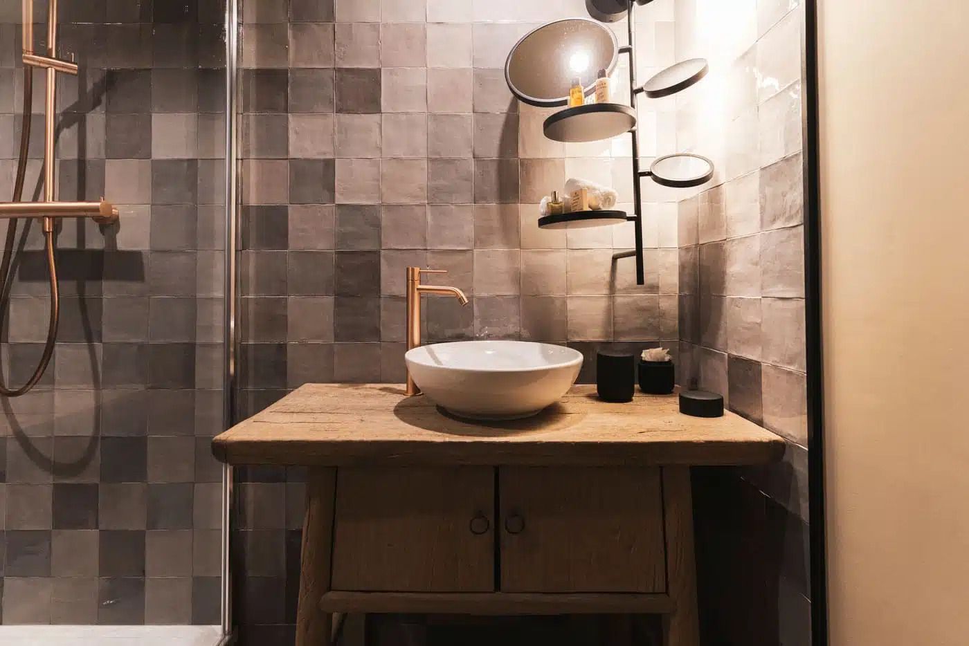Een badkamer met een wastafel in een bijzondere vorm, een handdouche en een spiegel aan de muur.