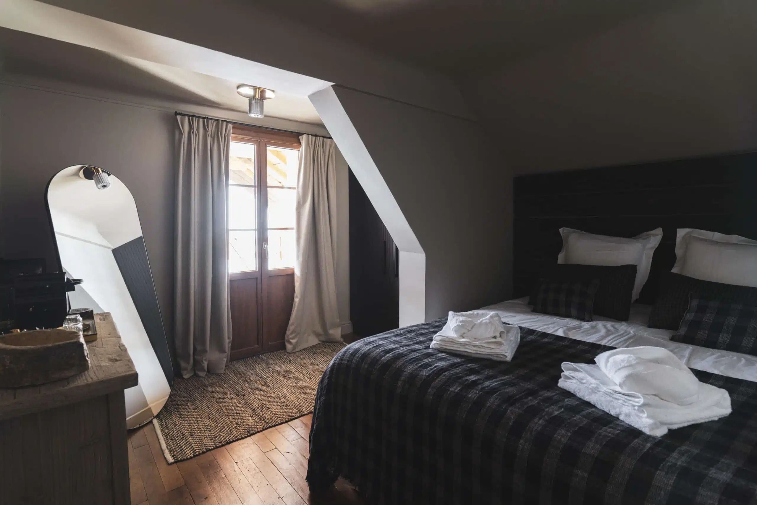 Een slaapkamer met een bed, een bureau en een raam met gordijnen.