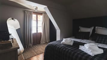 Een slaapkamer met een bed, een bureau en een raam met gordijnen.
