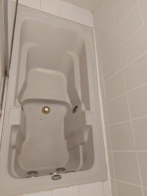 Een bad met afvoer, bedieningspaneel en een wateraansluiting.
