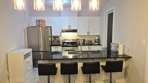 A modern kitchen with a central island, stainless steel appliances, and bar stools. - House in Orleans (Ottawa)