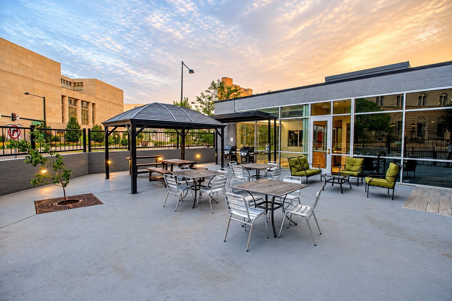 Outdoor patio with a gazebo, grills, dining tables, and lounge seating at sunset