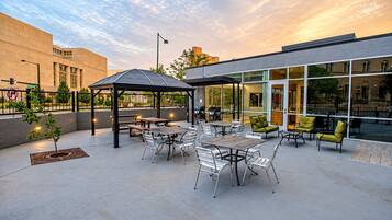 Outdoor patio with a gazebo, grills, dining tables, and lounge seating at sunset