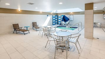 A pool area with lounge chairs and tables, a tiled floor, and a blue and white wall pattern.