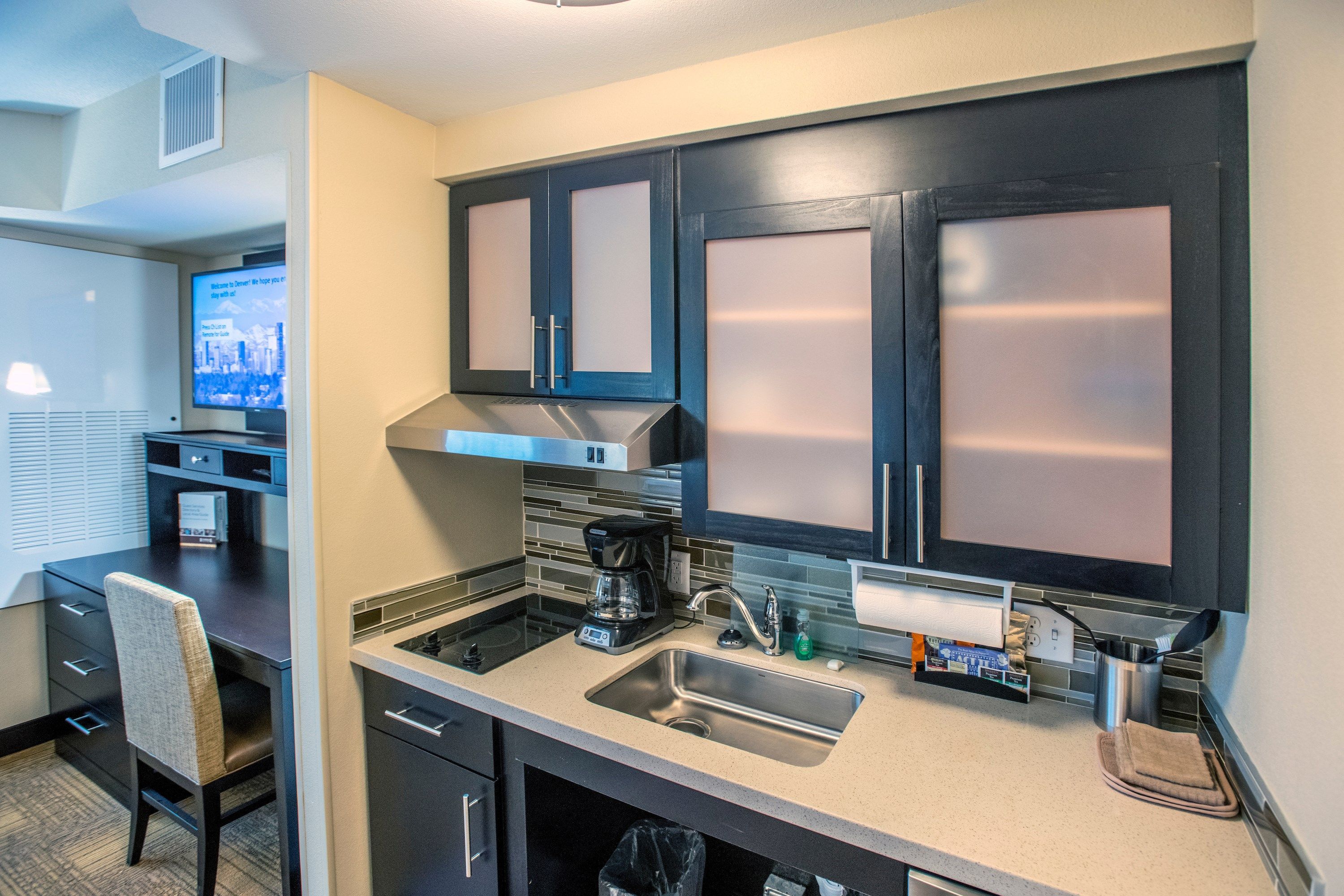 A modern kitchen with dark cabinets, stainless steel appliances, and a built-in oven.
